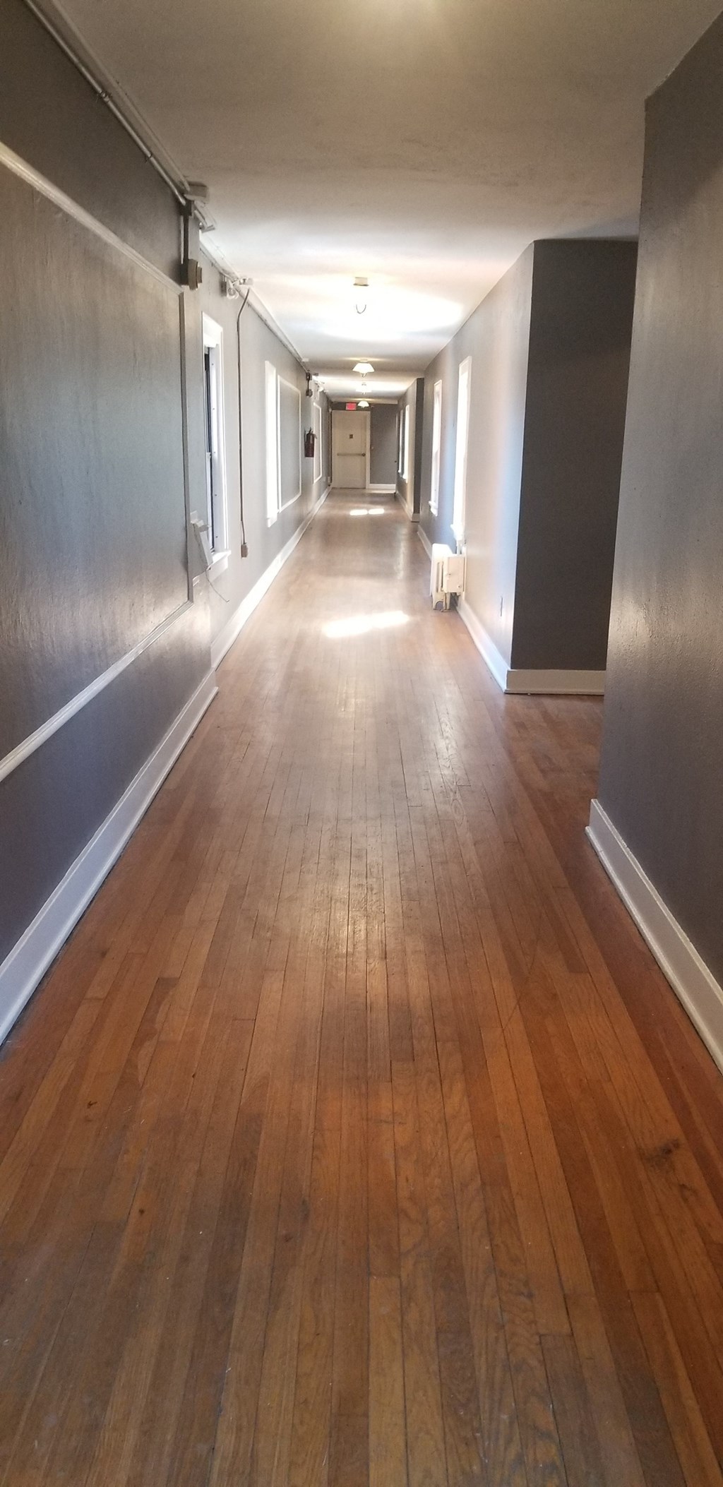 a long hallway with wood floors and grey walls and white walls