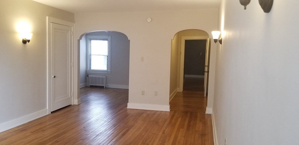 an empty living room with wood floors and white walls