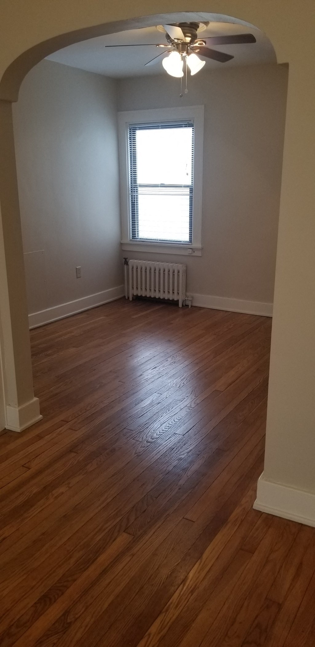 an empty living room with wooden floors and a window