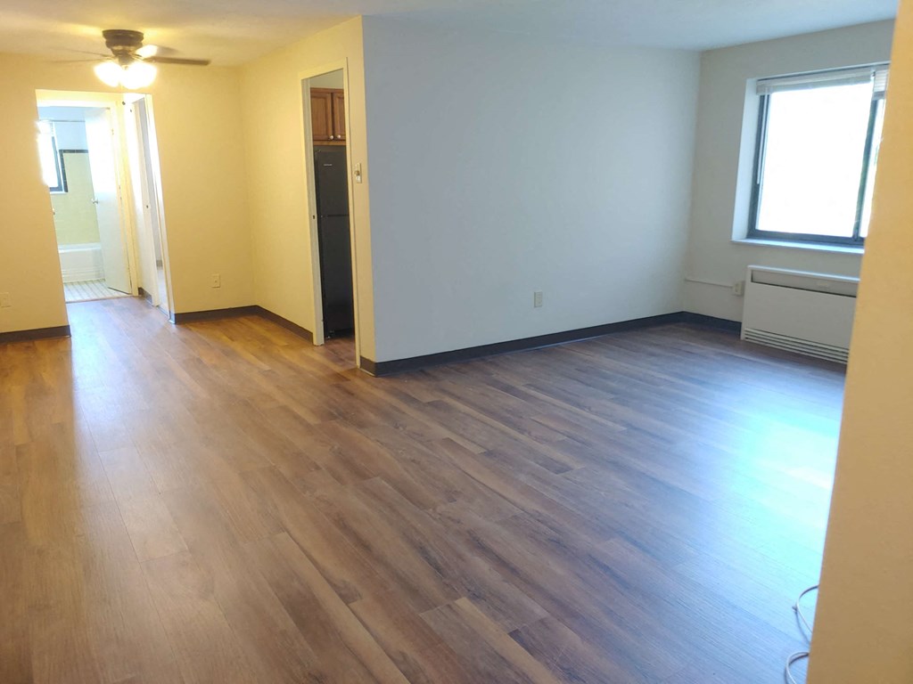 an empty living room with wooden floors and a window