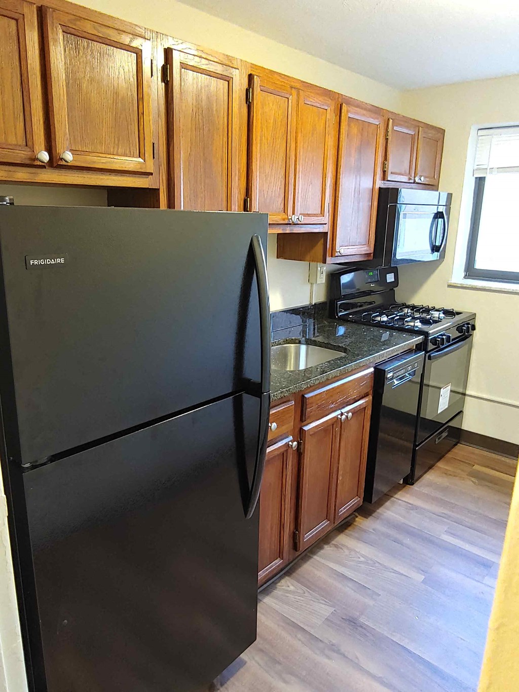 a kitchen with wooden cabinets and a black refrigerator
