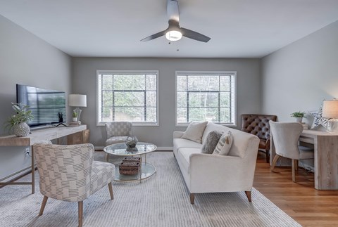 A living room with a white couch, a coffee table, and a ceiling fan.