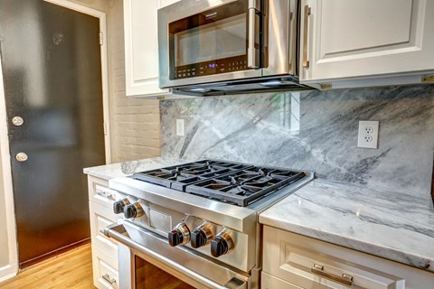A modern kitchen with a stove top oven and microwave above it.