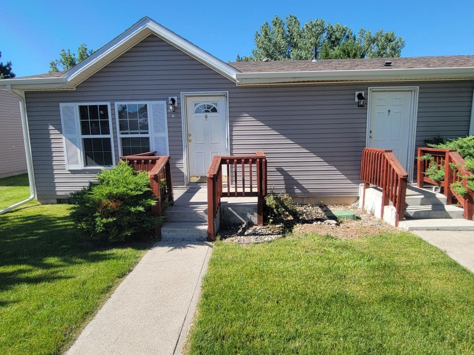 A house with a grey siding and a white door is shown.