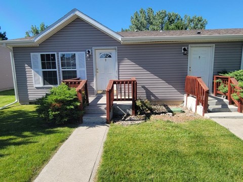 A house with a grey siding and a white door is shown.