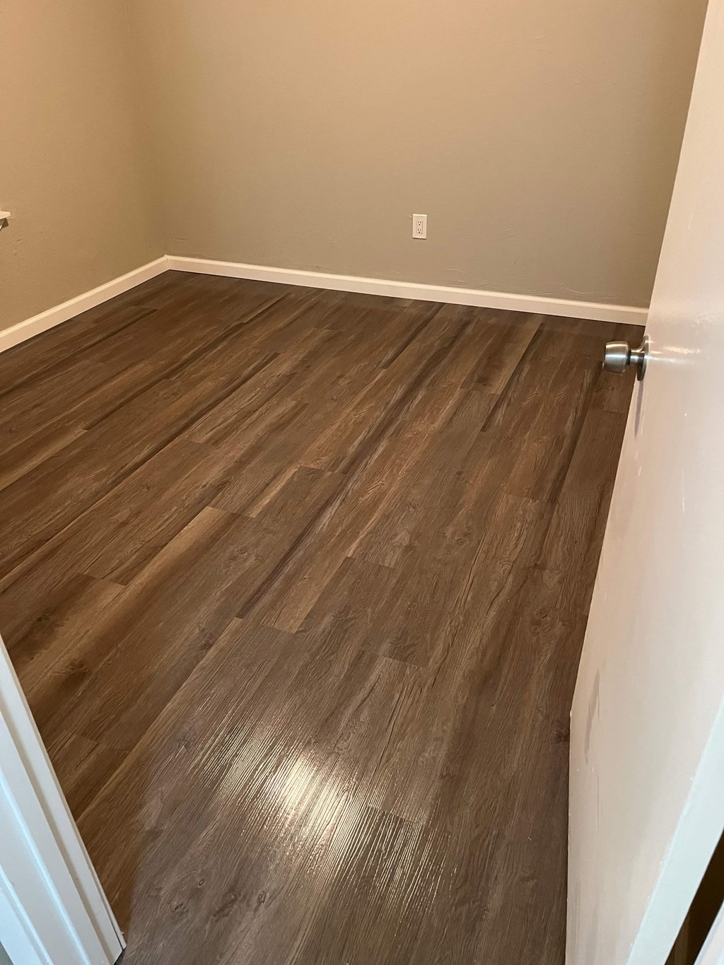 A room with a wooden floor and a white door.