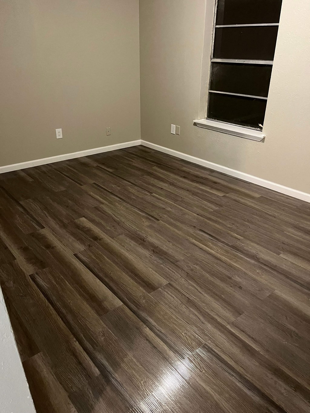 A room with a wooden floor and a window.