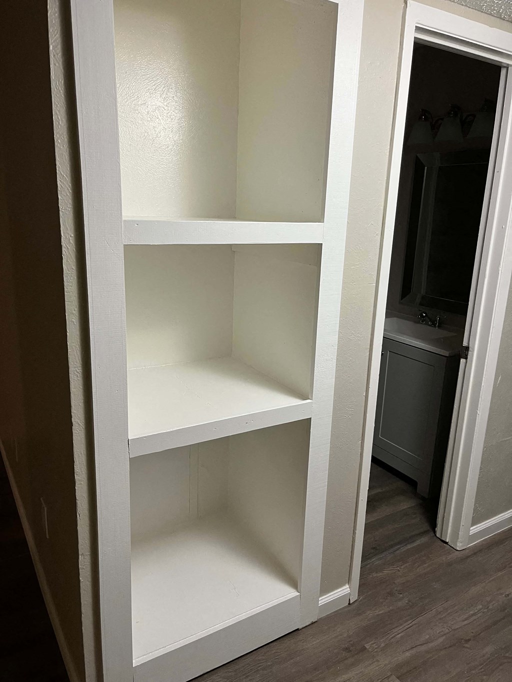 A white shelving unit with four shelves is open to the right.