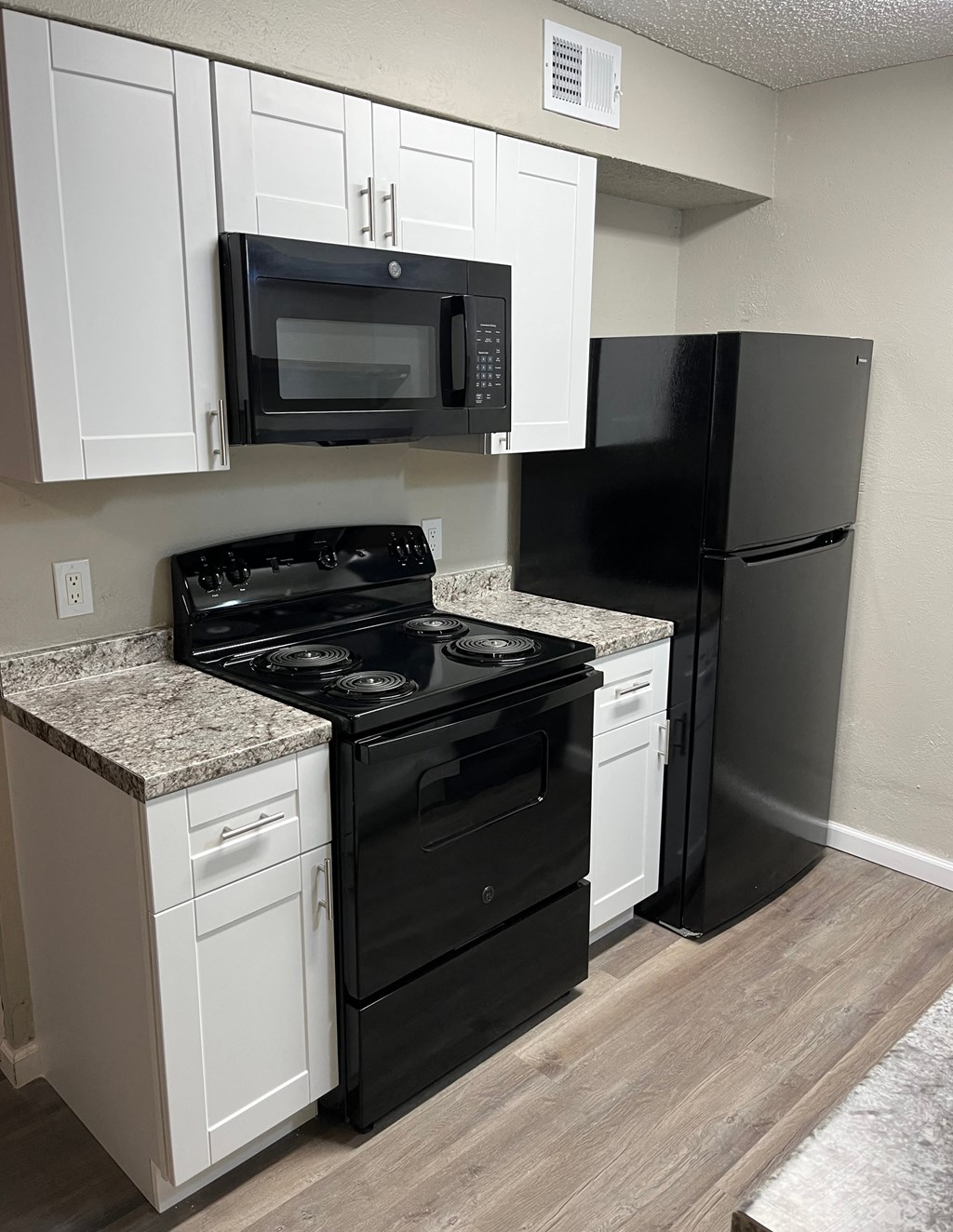 A black refrigerator stands next to a black stove in a kitchen.
