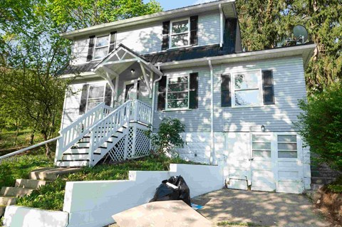 a blue house with the front porch removed and the steps up to it