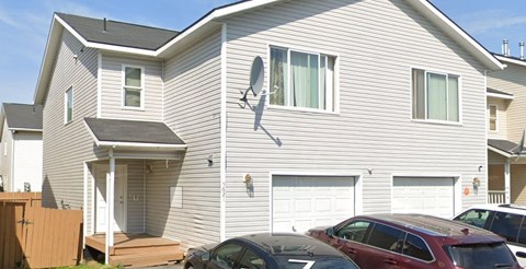 A house with a garage and a car parked in front.