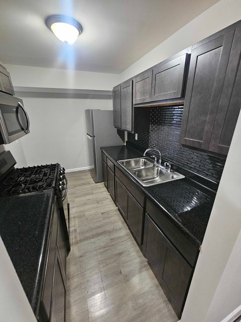 A kitchen with black cabinets and a black counter top.