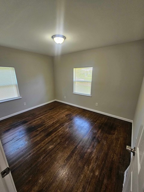 A room with wooden flooring and a window with blinds.