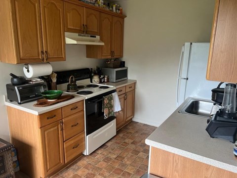 A kitchen with wooden cabinets and a tile floor.