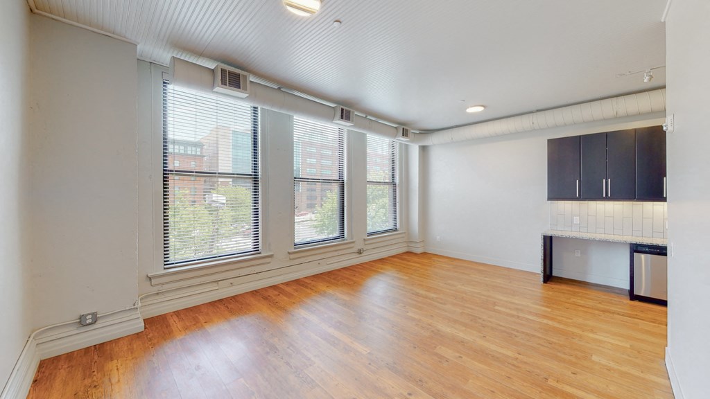 an empty living room with wood floors and large windows