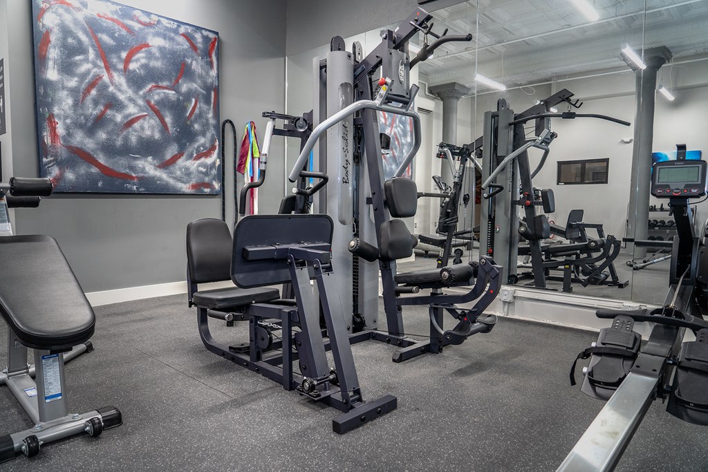 a gym with exercise equipment and a painting on the wall