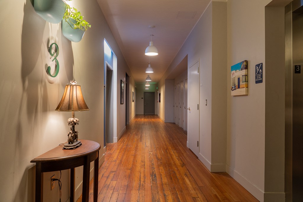 a hallway with wood floors and white walls and a lamp