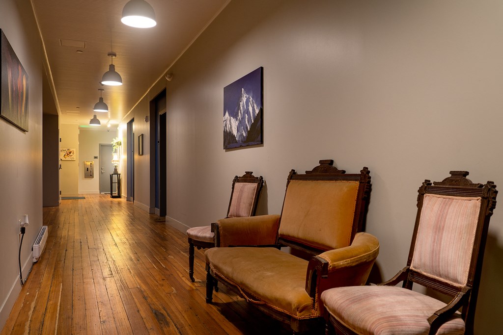 a long hallway with chairs and a painting on the wall