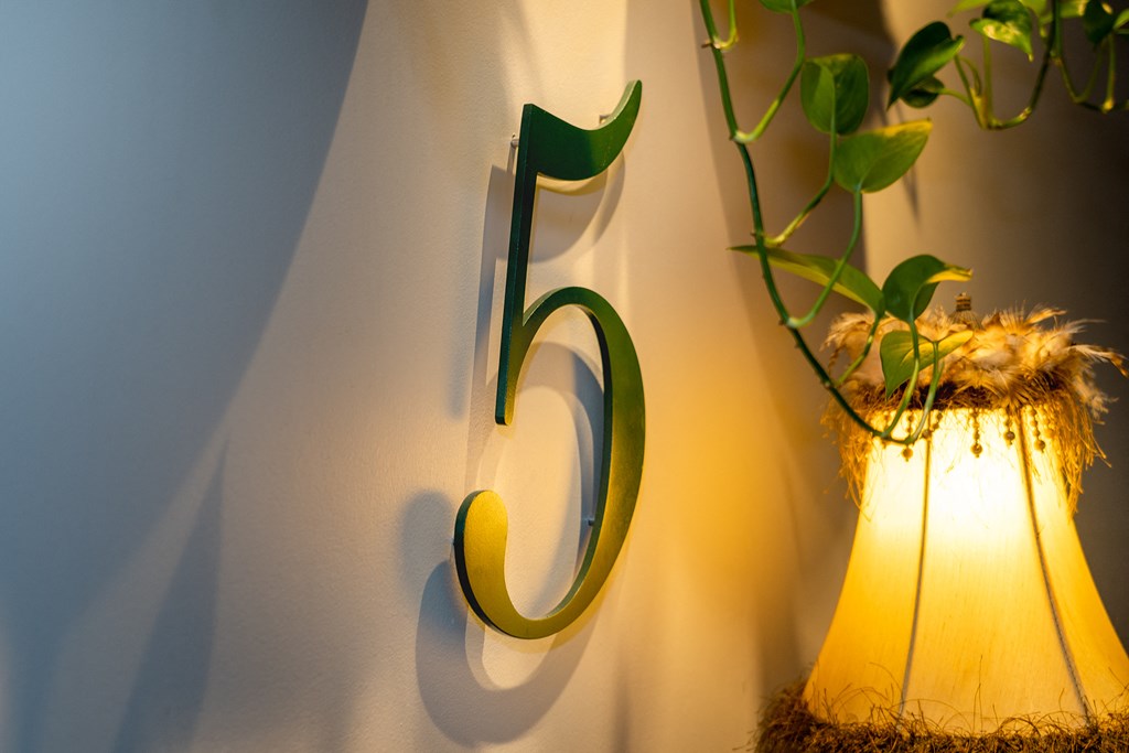 a metal wall mounted number six on a wall next to a lamp