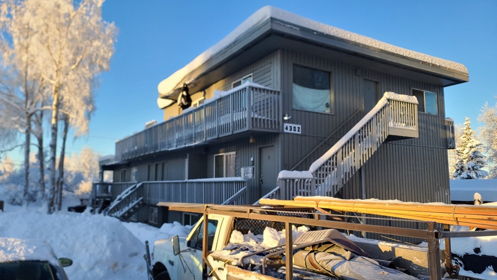 A house with a balcony and a snow-covered ground.