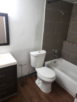 A white toilet sits in a bathroom next to a bathtub.