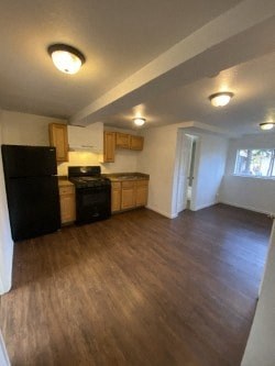 A kitchen with wooden floors and a black refrigerator.