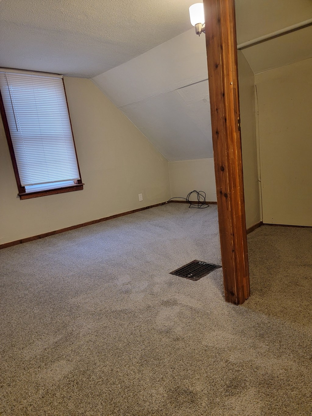 the living room of an empty house with carpet and a window
