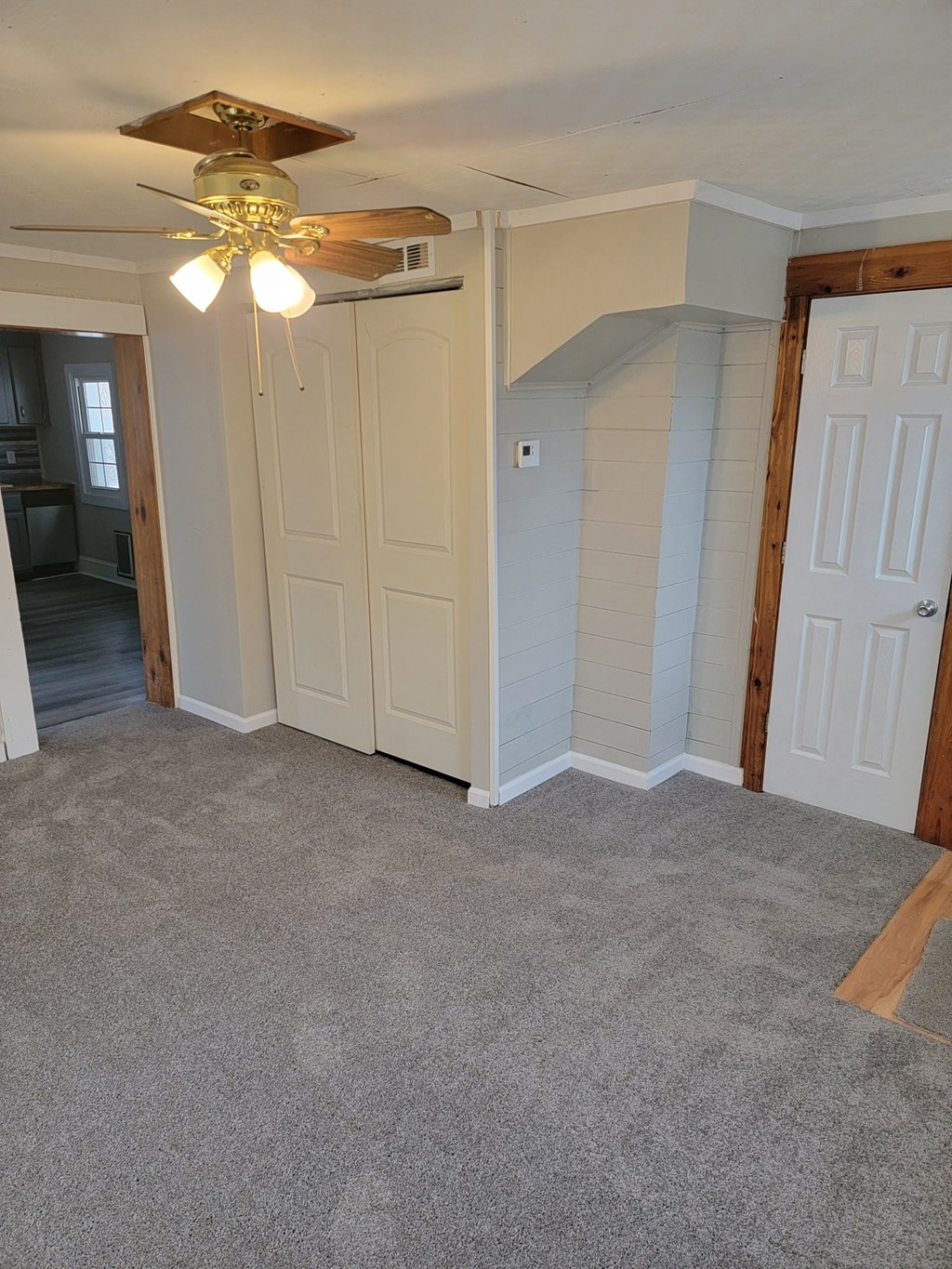 an empty room with a ceiling fan and a door to a closet
