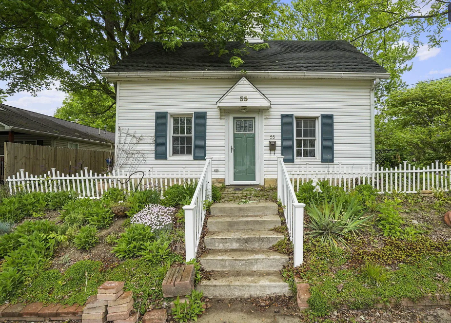 a small white house with steps and a green door
