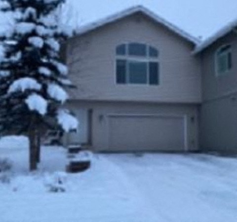 a house with a snow covered yard and a tree