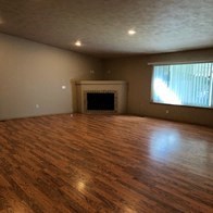 an empty living room with wooden floors and a fireplace