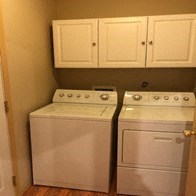 a kitchen with two washing machines and white cabinets