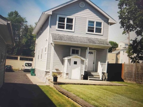 A house with a grey roof and white walls with a small porch.
