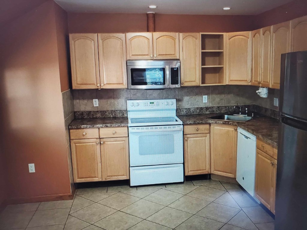 A kitchen with wooden cabinets and a white oven.