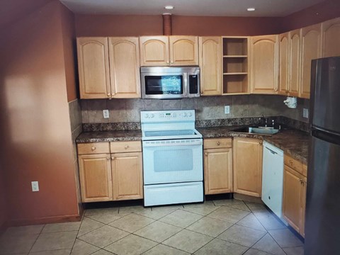 A kitchen with wooden cabinets and a white oven.
