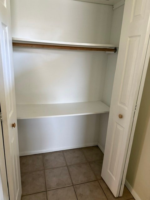 A white closet with a shelf and a door.