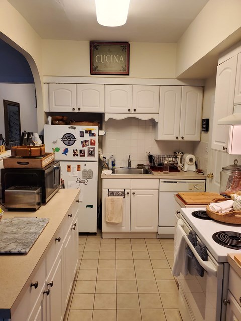 A kitchen with a refrigerator covered in magnets and a sign that says "Cucina" above it.
