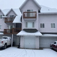 A white car is parked in front of a garage.