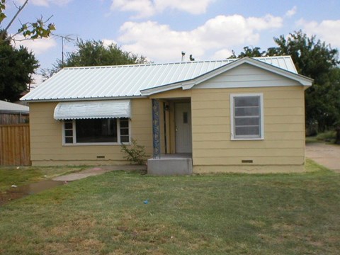a small yellow house with a tin roof