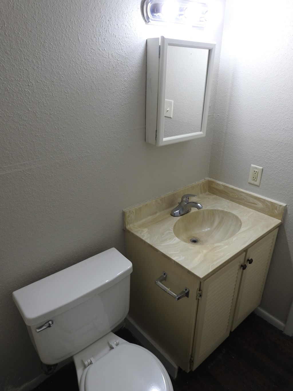 A white toilet sits next to a wooden sink in a small bathroom.