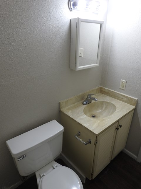 A white toilet sits next to a wooden sink in a small bathroom.