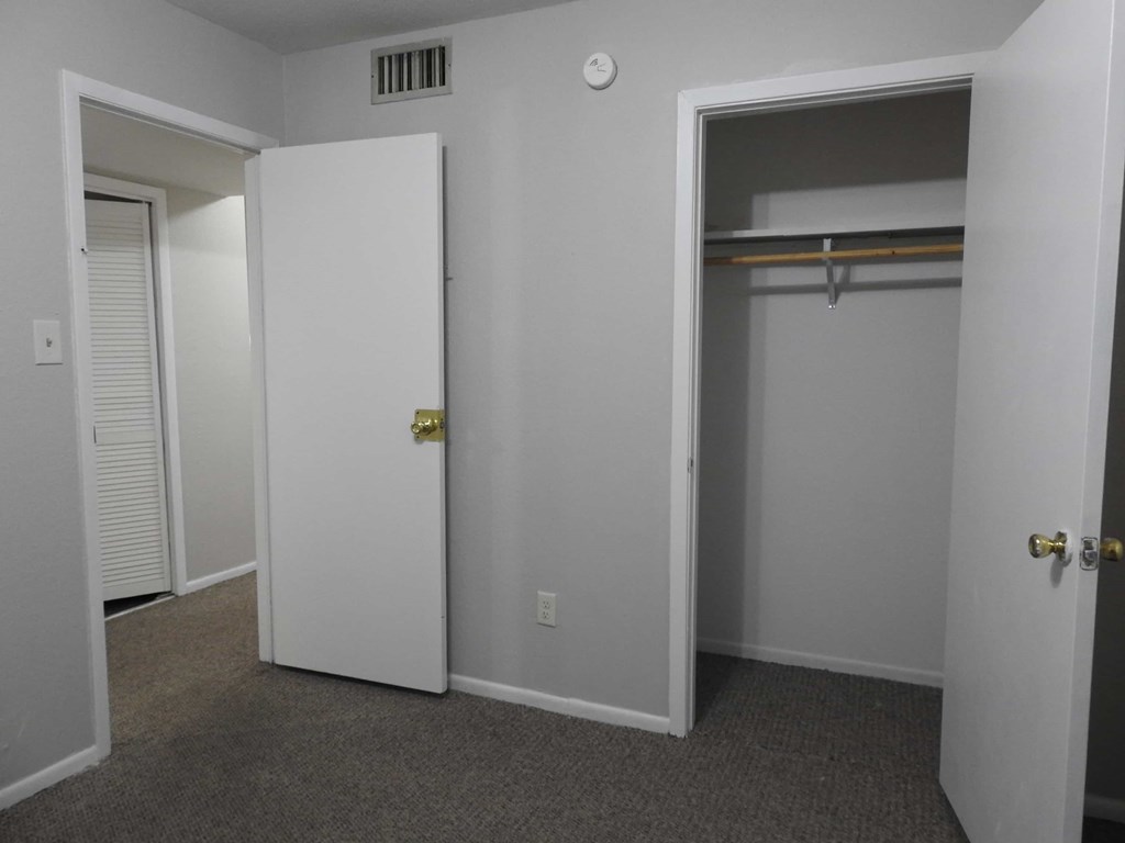 A white door with a gold handle is open to a room with a grey carpet.