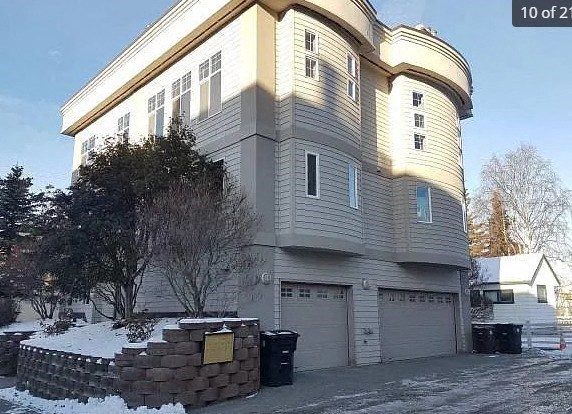 a white house with a garage in the snow