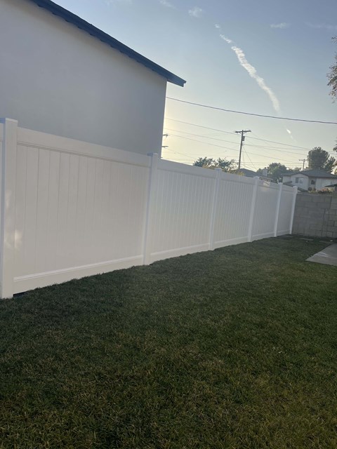 a white fence in a backyard with green grass