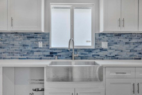 a white kitchen with white cabinets and a stainless steel sink