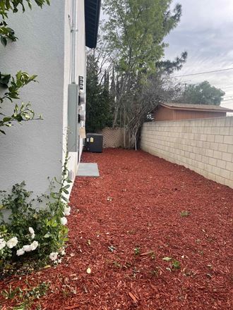 a side yard with a brick wall and mulch next to a house