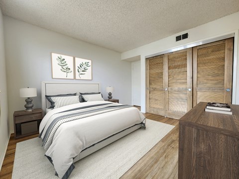 A bedroom with a large bed, a nightstand with a lamp, and a wooden dresser with a book on top.
