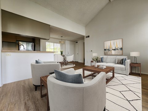 A living room with a white couch, a grey armchair, a coffee table, and a painting on the wall.
