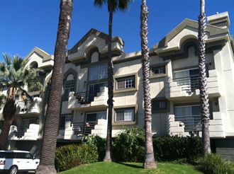 an apartment building with palm trees in front of it