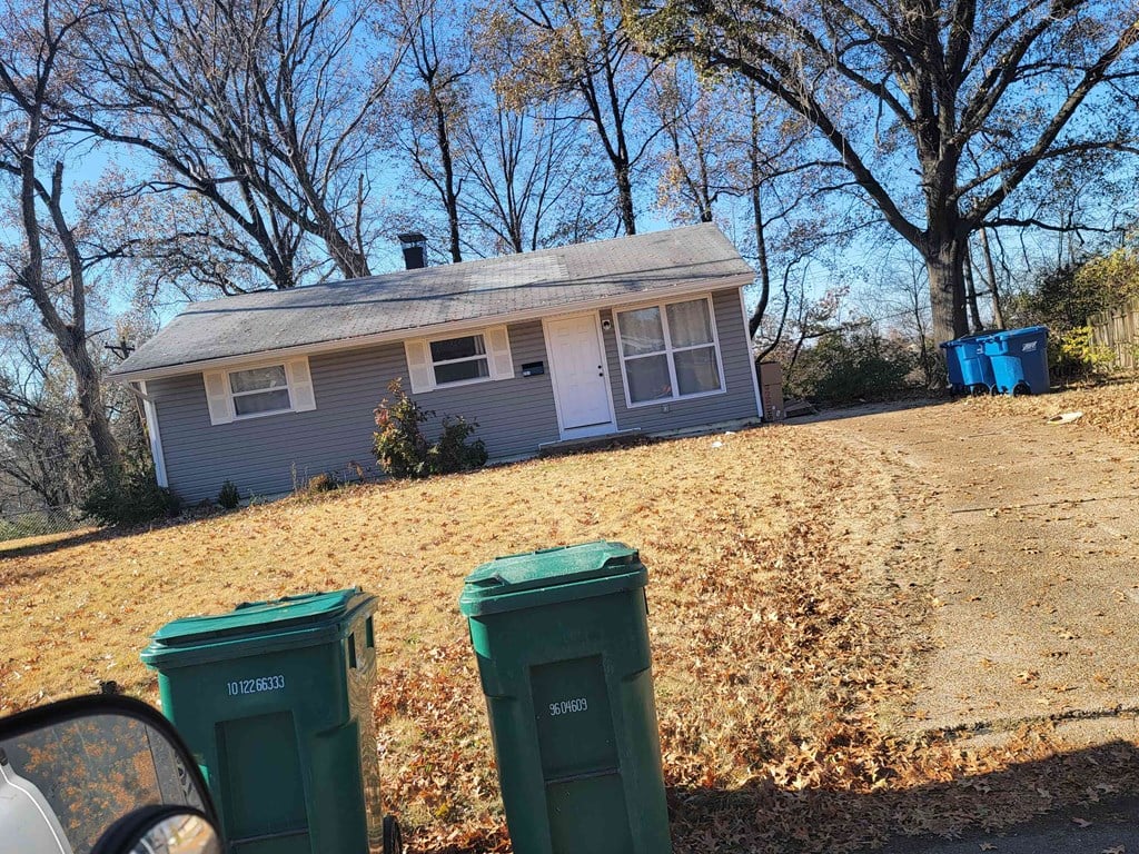 a house on a hill with trash cans in front of it